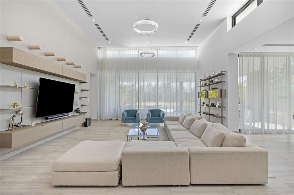A modern living room features a large sectional sofa, a wall-mounted television, and floor-to-ceiling curtains — 13 SALT LANE, THE ISLES AT DORADO BEACH, DORADO, PR