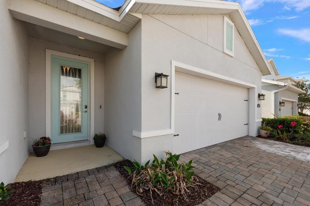 A light-colored house exterior features a light blue front door and a white garage door — 12353 BLUE PACIFIC DRIVE, RIVERVIEW, FL