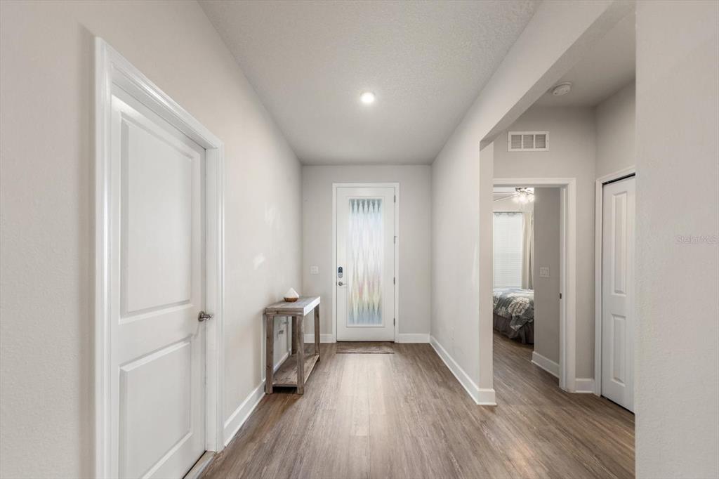 A bright entryway features light-colored walls, wood-look flooring, a front door, and interior doors — 12353 BLUE PACIFIC DRIVE, RIVERVIEW, FL