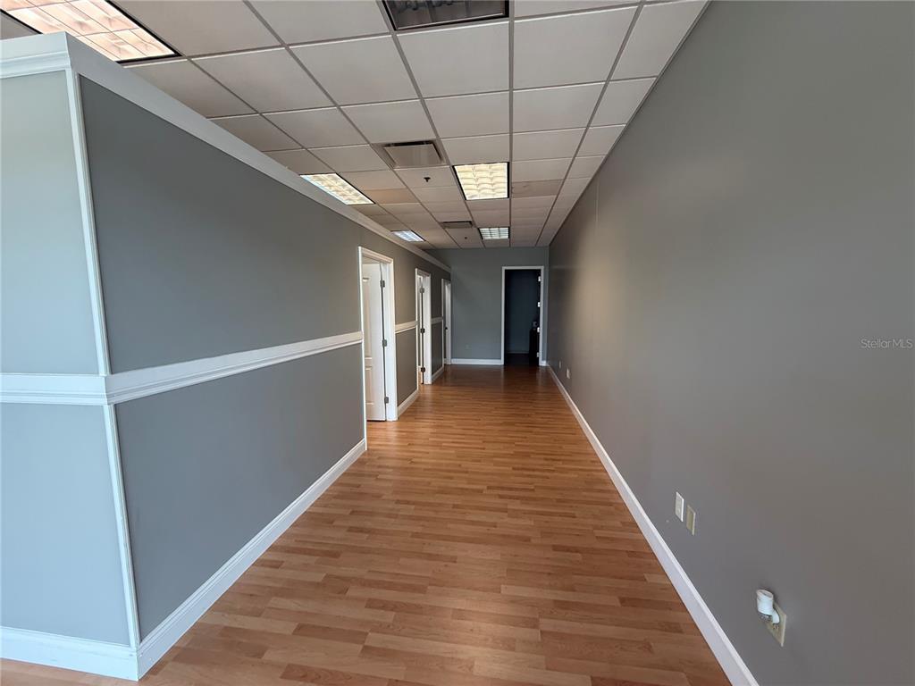 An office space features light wood flooring, gray walls, a drop ceiling, and several doorways — 10967 LAKE UNDERHILL ROAD UNIT 106, ORLANDO, FL