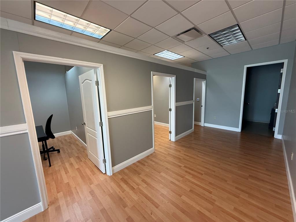 A hallway with wood-look flooring, gray walls, white trim, and a drop ceiling with lights — 10967 LAKE UNDERHILL ROAD UNIT 106, ORLANDO, FL