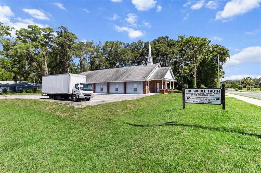 A church building with a white steeple stands next to a parked box truck — 1601 NW 14TH STREET, OCALA, FL