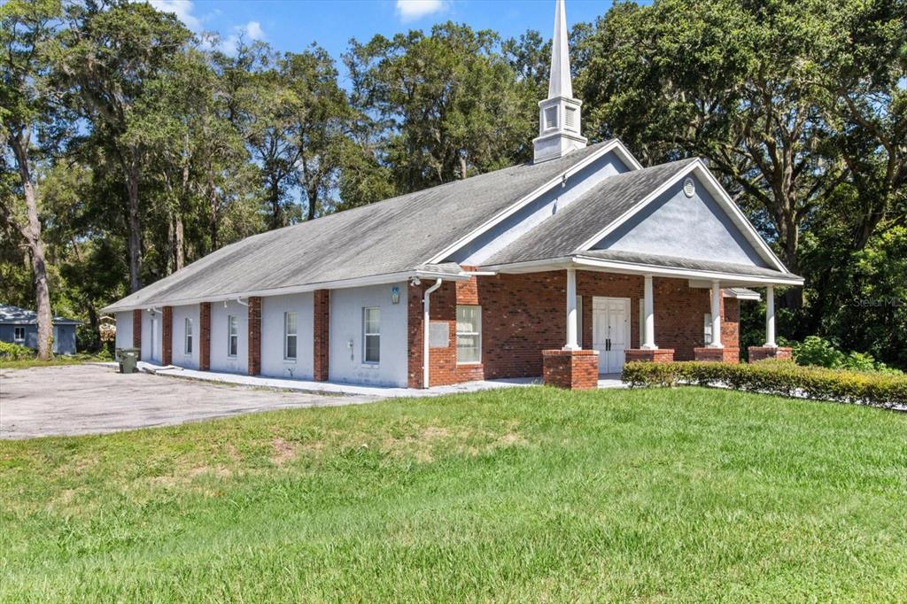 A brick and light-colored building with a steeple sits on a grassy lot with trees — 1601 NW 14TH STREET, OCALA, FL