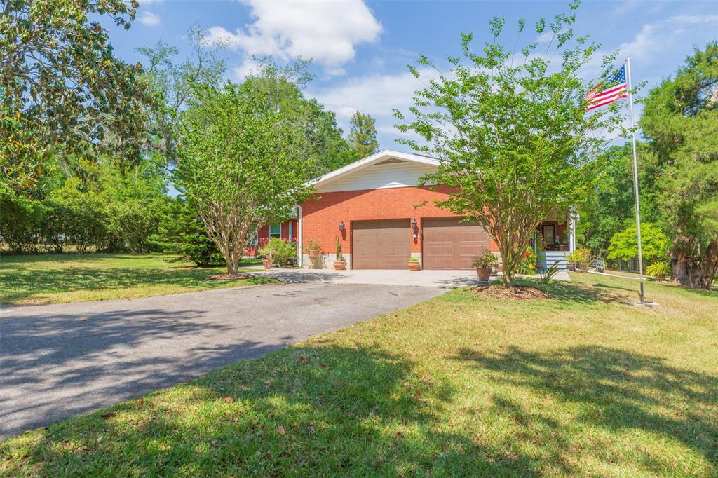 A brick house with a two-car garage and a flag pole in the front yard — 34211 BLANTON ROAD, DADE CITY, FL