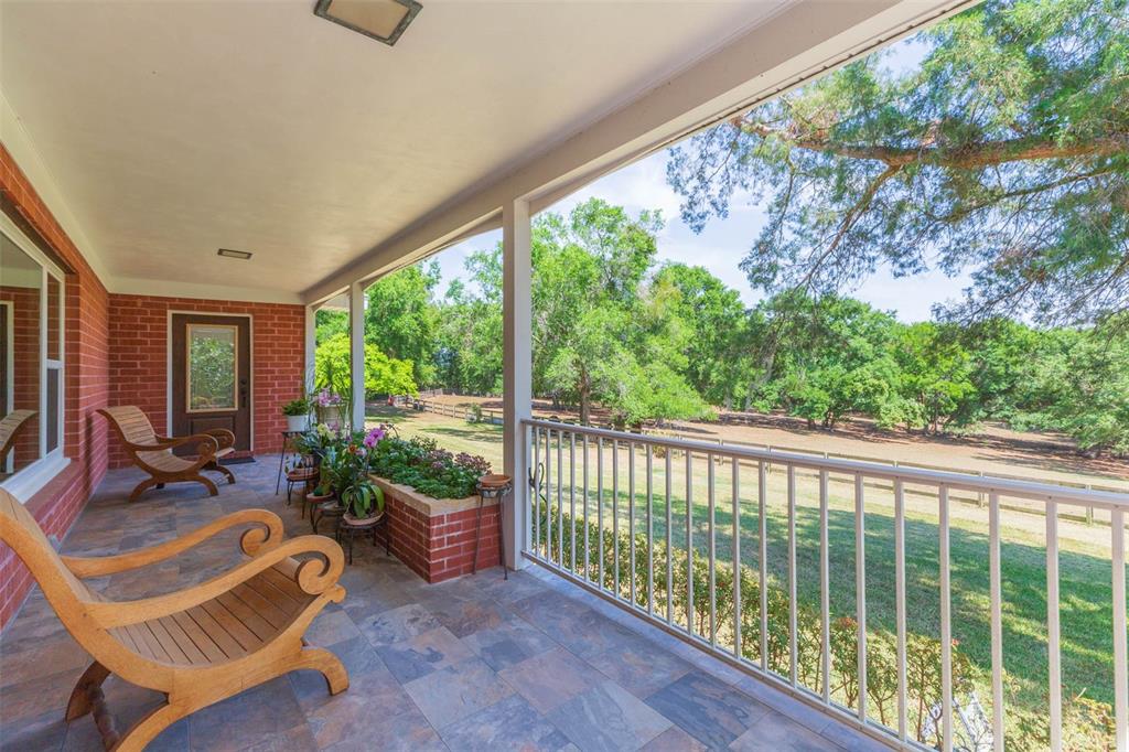 A covered brick porch features tile flooring, wooden lounge chairs, and a metal railing — 34211 BLANTON ROAD, DADE CITY, FL