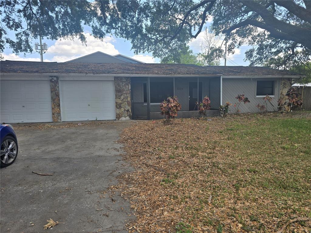 A single-story house with a two-car garage, stone accents, and a screened-in front porch — 6124 11TH STREET, ZEPHYRHILLS, FL