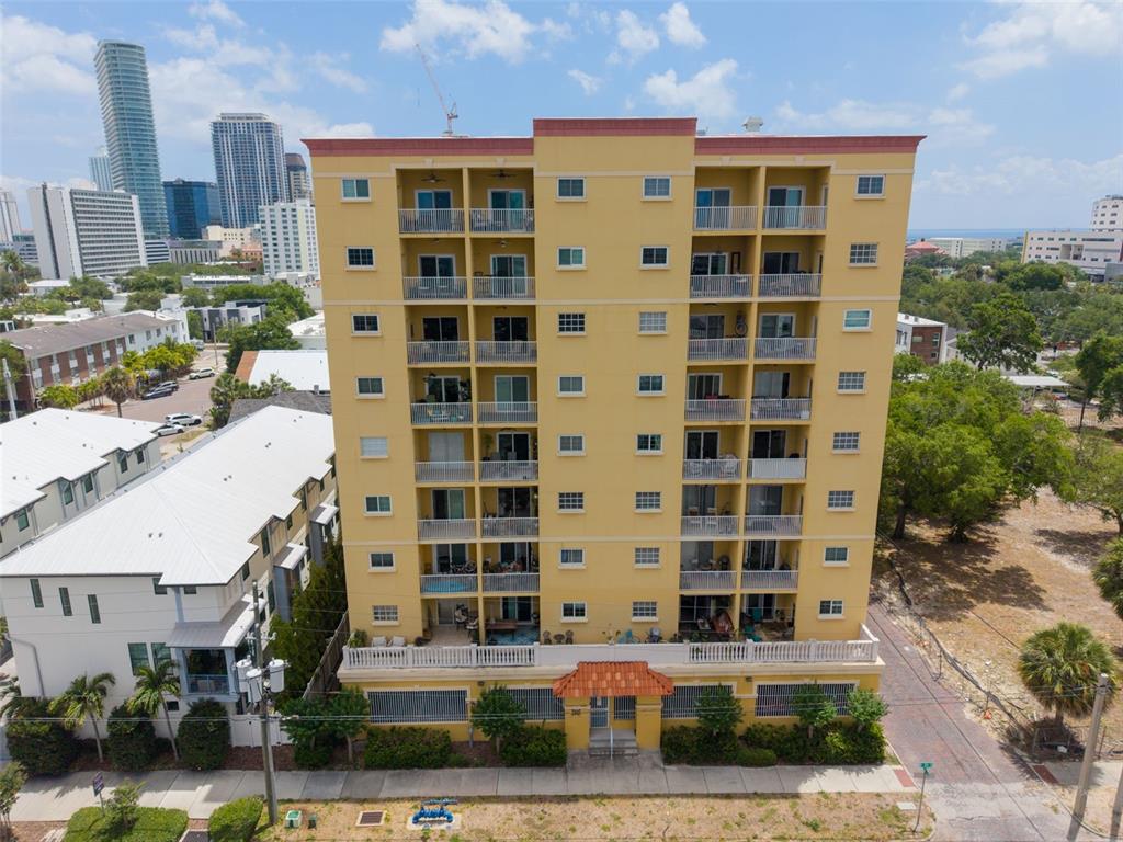 An aerial view shows a yellow multi-story residential building with balconies and a ground-level entrance — 316 8TH STREET S UNIT 604, ST PETERSBURG, FL