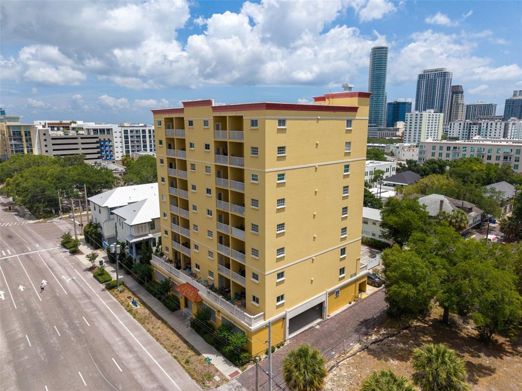 An aerial view shows a yellow multi-story apartment building next to a city street — 316 8TH STREET S UNIT 604, ST PETERSBURG, FL