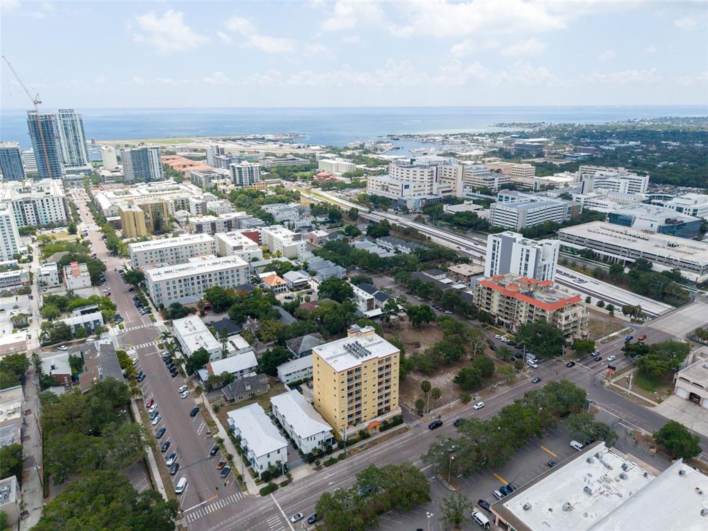An aerial view shows a city neighborhood with mid-rise buildings, streets, and a distant coastline — 316 8TH STREET S UNIT 604, ST PETERSBURG, FL