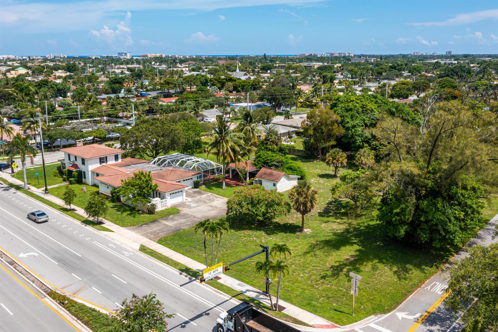 An aerial view shows a house with a pool enclosure and a large grassy yard — 556 E Hillsboro Boulevard, Deerfield Beach FL 33441, DEERFIELD BEACH, FL