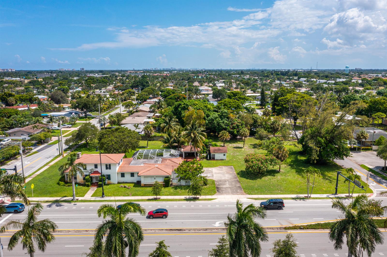 An aerial view shows a single-story house with a tiled roof and pool enclosure — 556 E Hillsboro Boulevard, Deerfield Beach FL 33441, DEERFIELD BEACH, FL