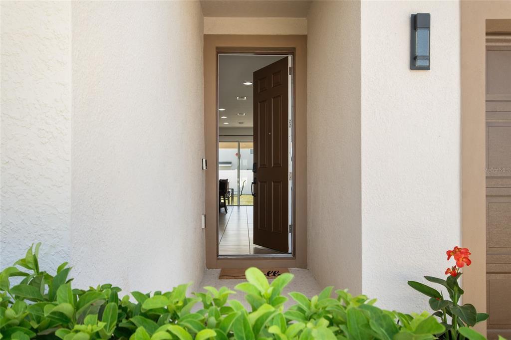 A brown front door stands open, revealing a view into the home's interior — 1659 GENTLE BREEZE DRIVE, ST CLOUD, FL