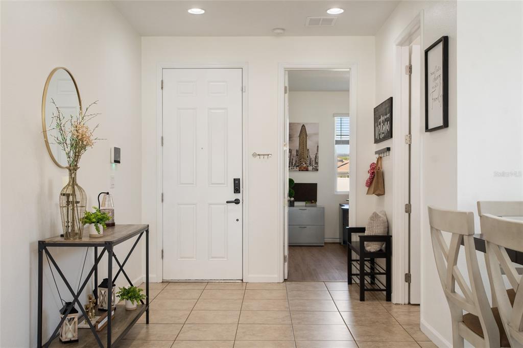 A bright entryway features tile flooring, a console table, a white door, and a doorway — 1659 GENTLE BREEZE DRIVE, ST CLOUD, FL