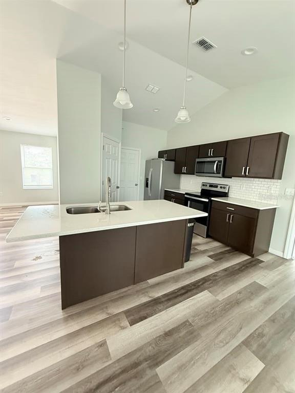 A kitchen features dark wood cabinets, a white quartz island, and light wood-look flooring — 6823 SW 129TH STREET, OCALA, FL