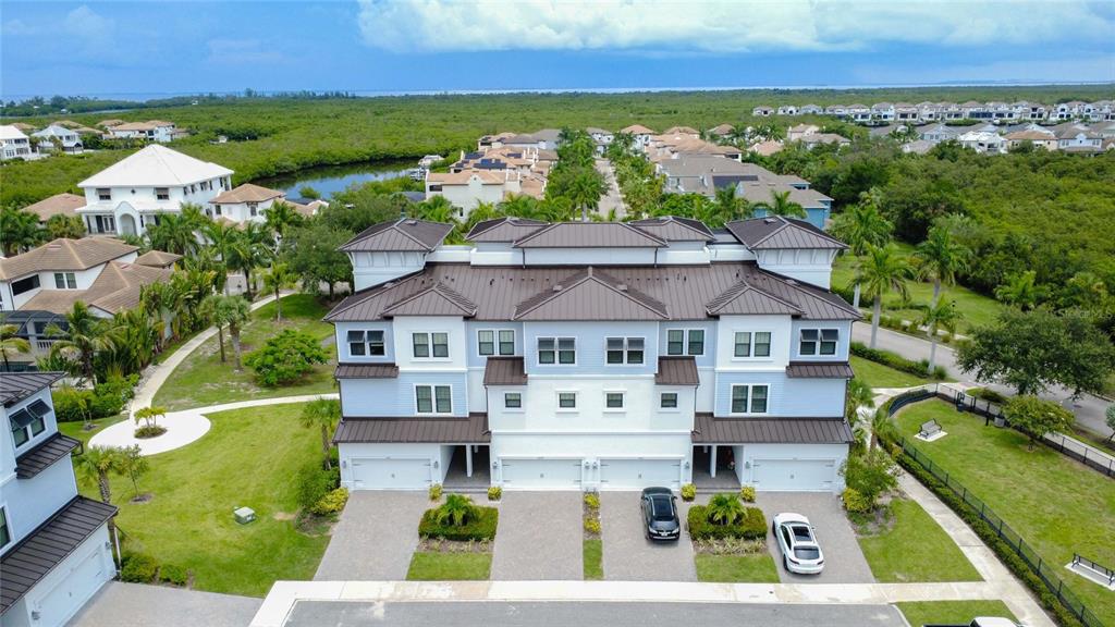 An aerial view of a three-story townhouse complex with light blue siding and metal roofs — 3023 BERMUDA SLOOP CIRCLE, RUSKIN, FL
