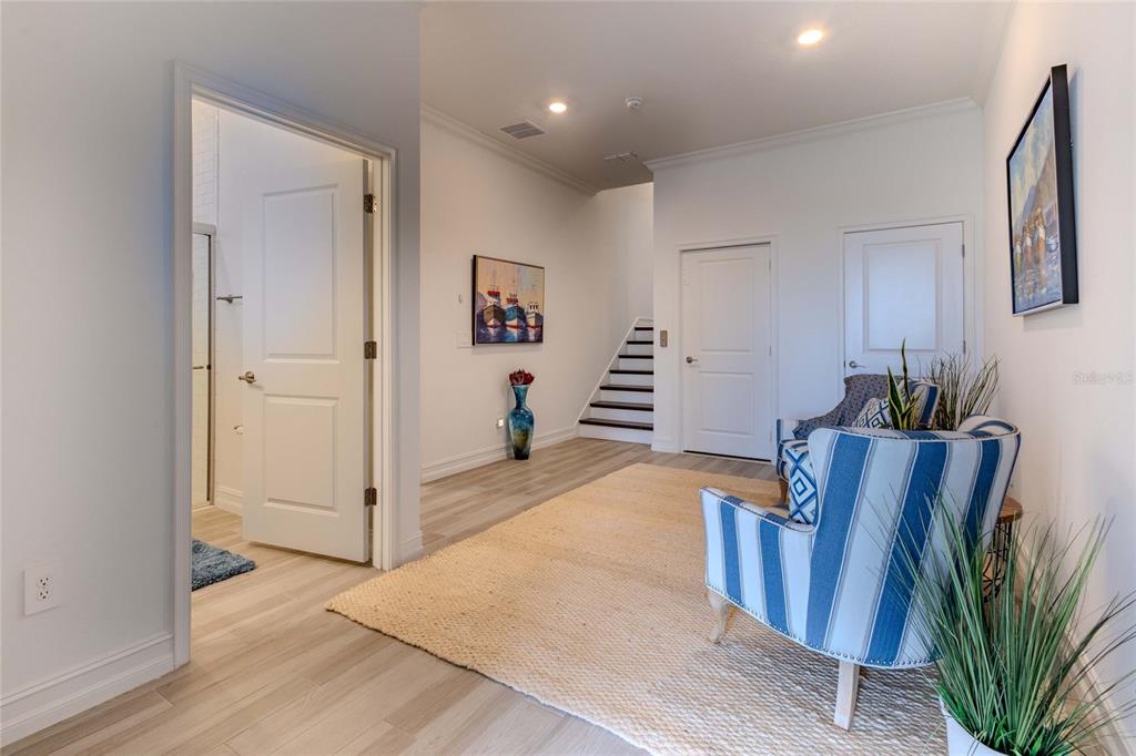 A bright hallway features light wood-look flooring, two blue striped armchairs, and a staircase — 3023 BERMUDA SLOOP CIRCLE, RUSKIN, FL