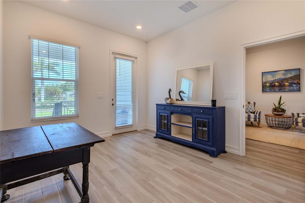 A room with light wood-look flooring, a dark blue console table, and a wooden table — 3023 BERMUDA SLOOP CIRCLE, RUSKIN, FL