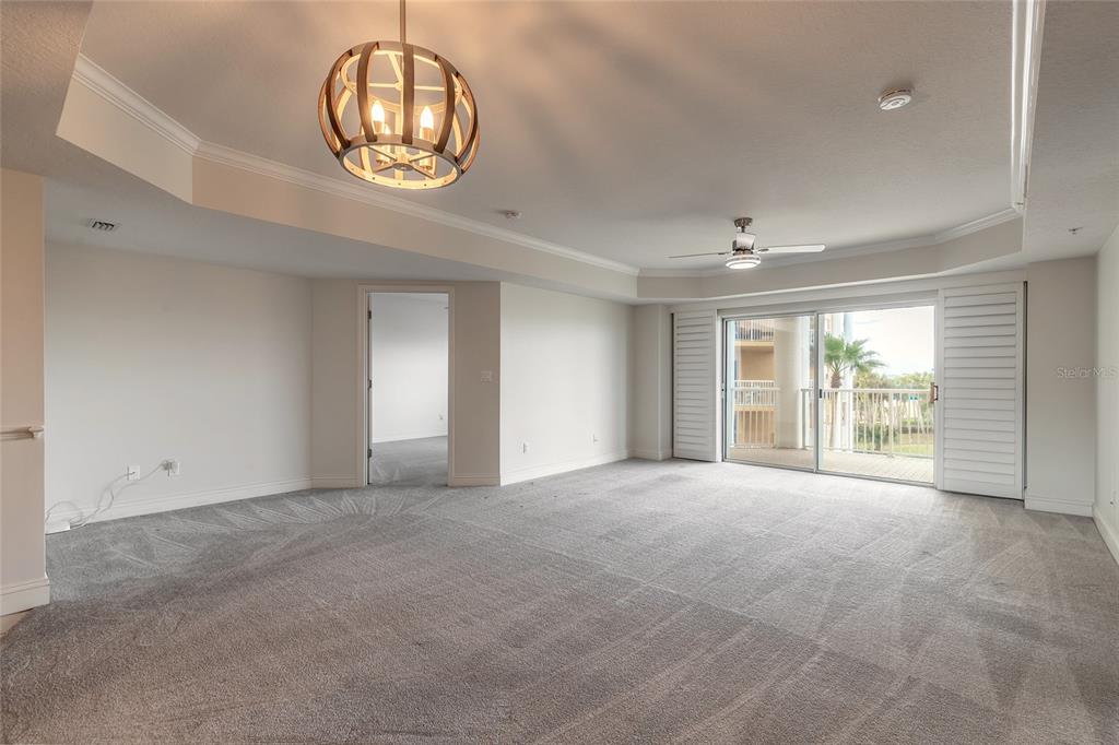 A carpeted living room features a wooden orb chandelier, a ceiling fan, and sliding glass doors — 4650 LINKS VILLAGE DRIVE UNIT A401, PONCE INLET, FL