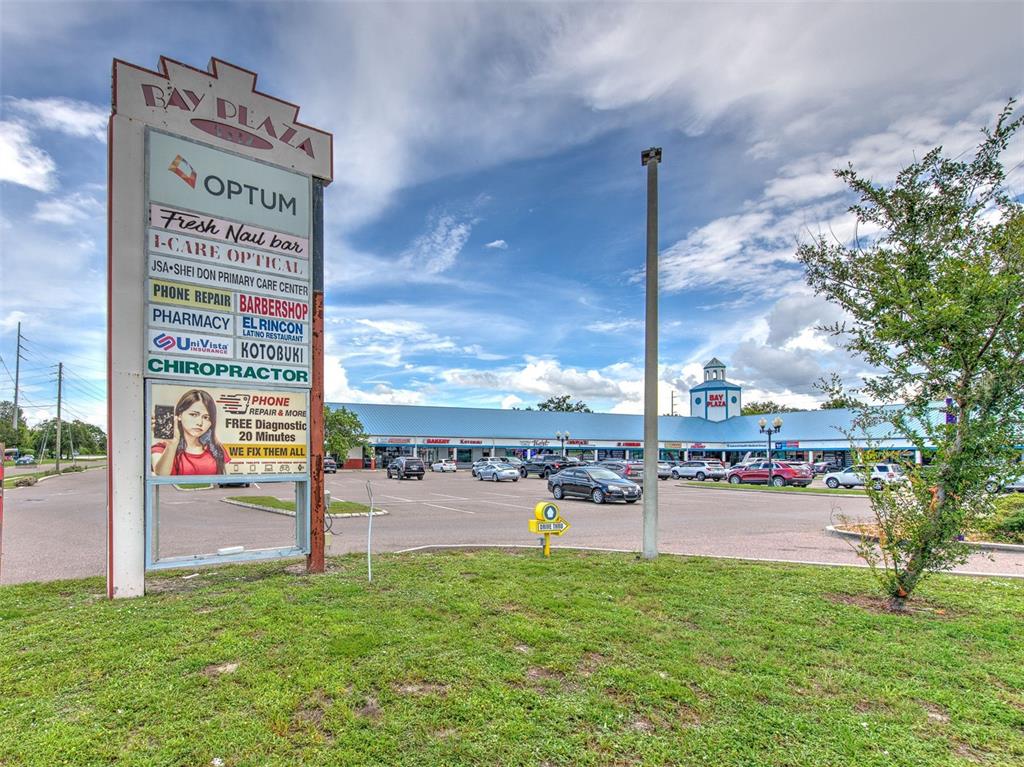 A large shopping center sign stands in front of a parking lot and retail building — 5537 SHELDON ROAD UNIT V, TAMPA, FL