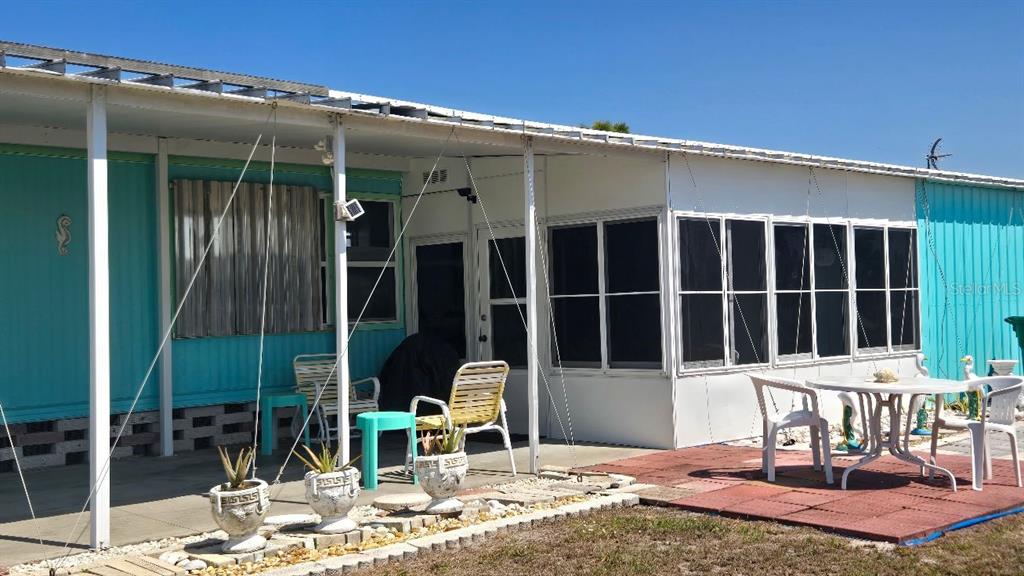A mobile home features a covered patio, screened-in porch, and outdoor furniture on a concrete slab — 1393 MALLARD DRIVE, ENGLEWOOD, FL