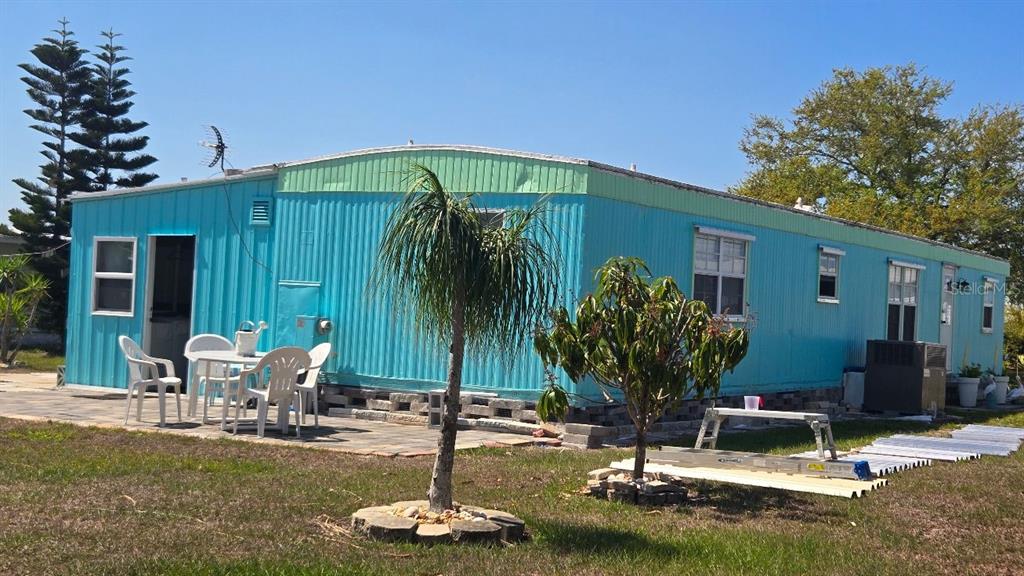 A bright blue mobile home sits on a grassy lot with a paved patio area — 1393 MALLARD DRIVE, ENGLEWOOD, FL