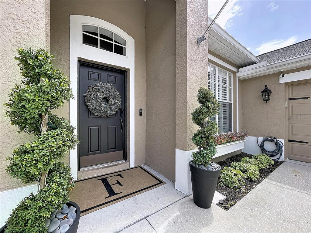 A front entryway features a black door, a monogrammed mat, and two spiral topiary plants — 1748 BROOKSTONE WAY, PLANT CITY, FL