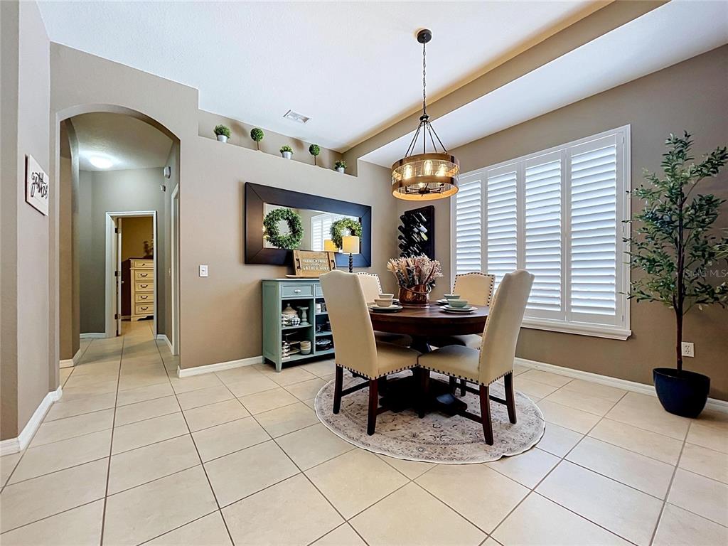 A dining room features a round wooden table, upholstered chairs, a chandelier, and tile flooring — 1748 BROOKSTONE WAY, PLANT CITY, FL