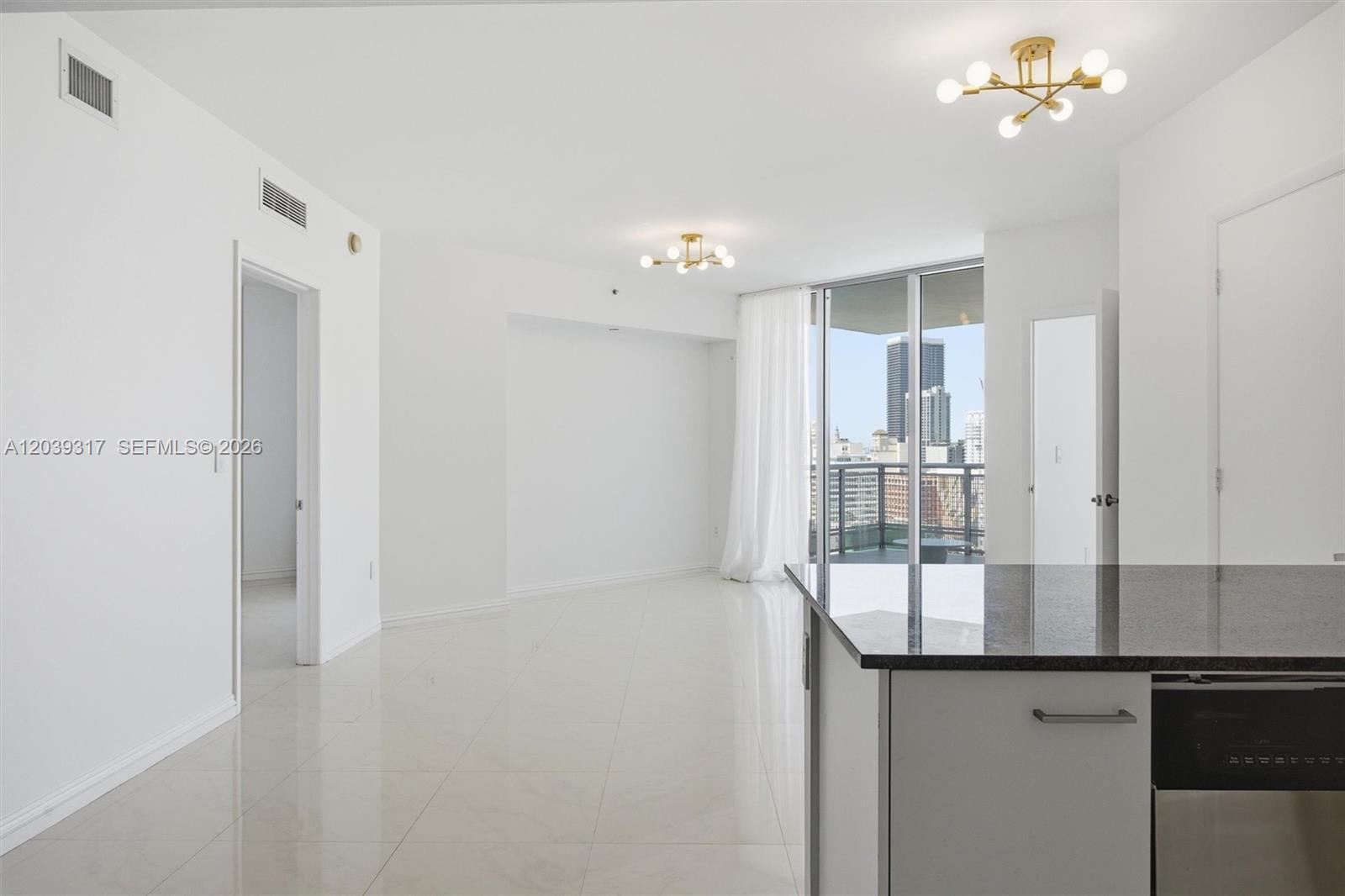 An open-concept living area features white tile floors, modern gold chandeliers, and a balcony view — 350 S Miami Ave # 1903, Miami FL 33130, MIAMI, FL