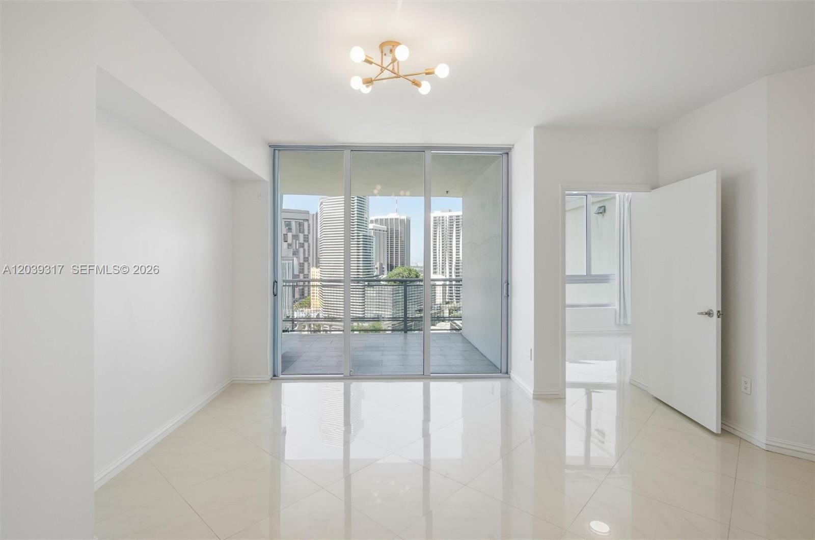 An empty room with white walls, tile floors, a modern light fixture, and a balcony — 350 S Miami Ave # 1903, Miami FL 33130, MIAMI, FL