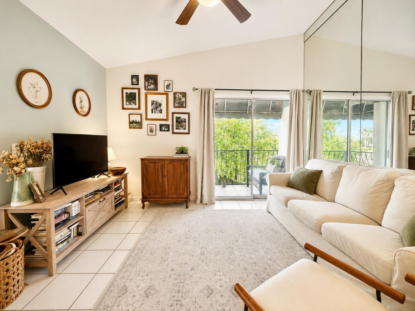A living room features a white sofa, a television on a wooden stand, and a balcony — 179 Waterside Drive # 179, Hypoluxo FL 33462, HYPOLUXO, FL
