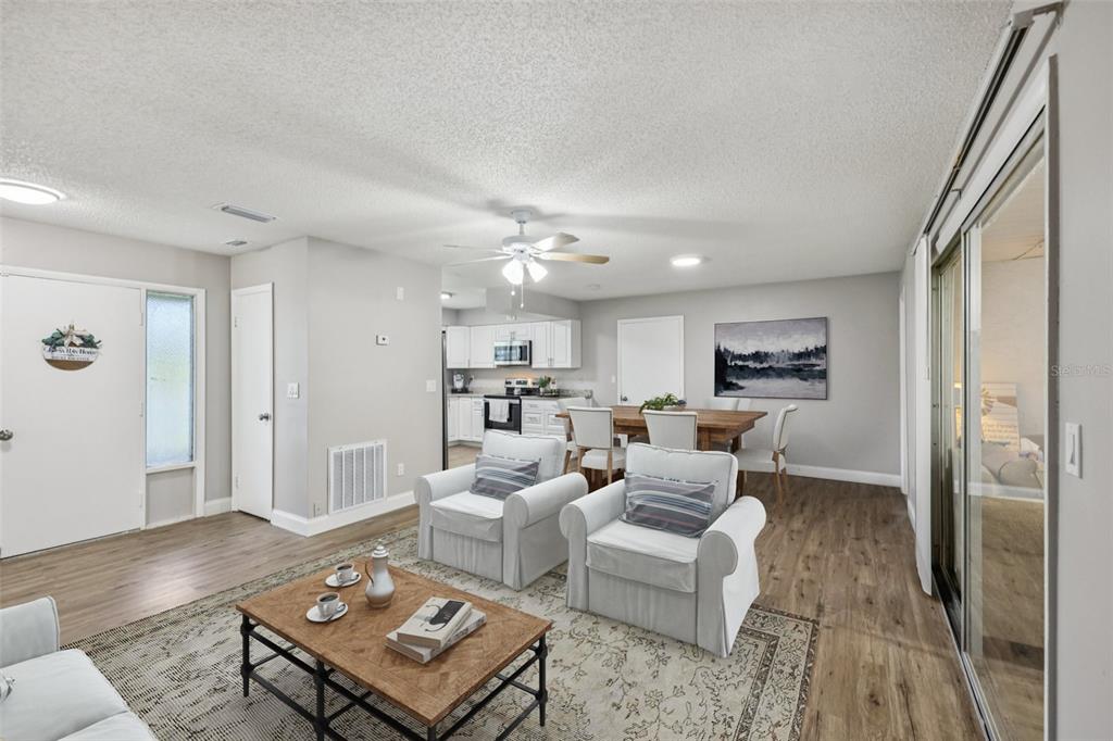A living room with light wood floors, two white armchairs, and an adjacent dining area — 3 SILVER COURT, OCALA, FL