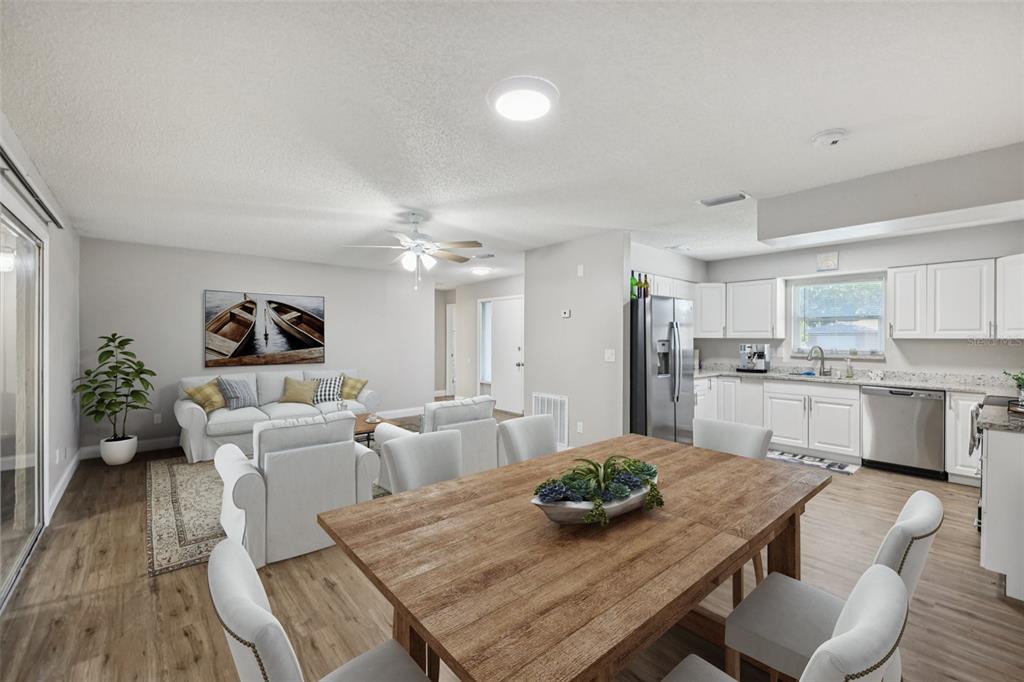 An open-concept living and dining area features wood-look flooring, white cabinetry, and a wooden table — 3 SILVER COURT, OCALA, FL