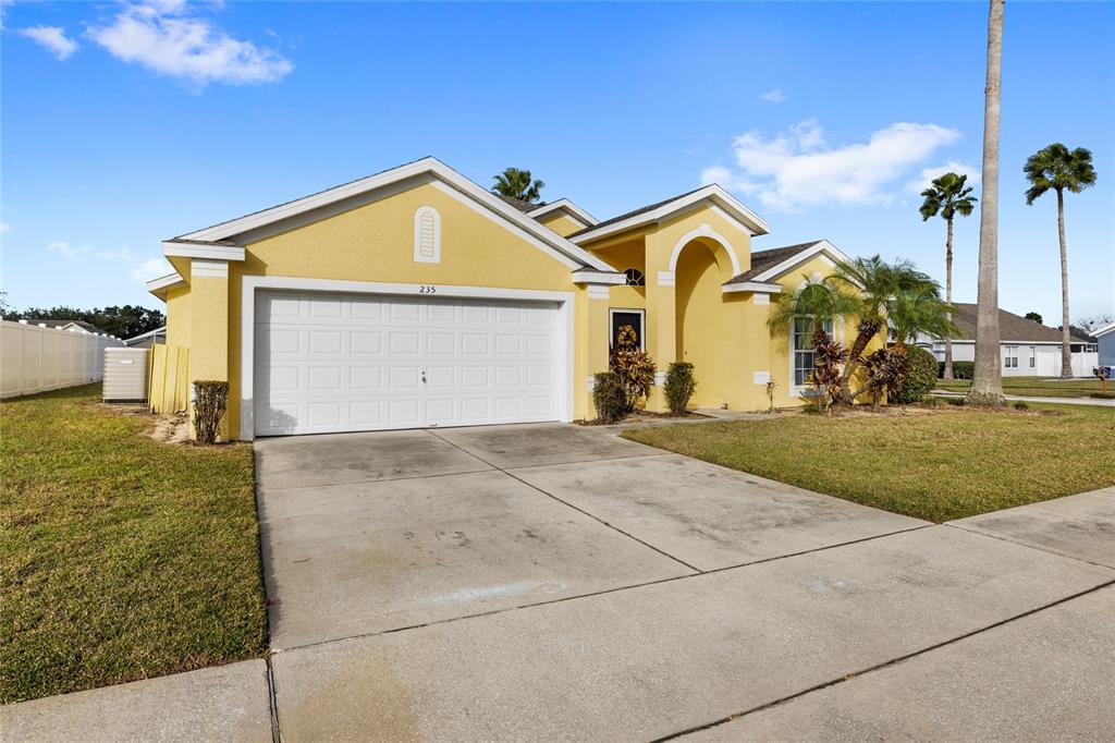 A yellow single-story house with a two-car garage and a concrete driveway — 235 BALLYSHANNON DRIVE, DAVENPORT, FL