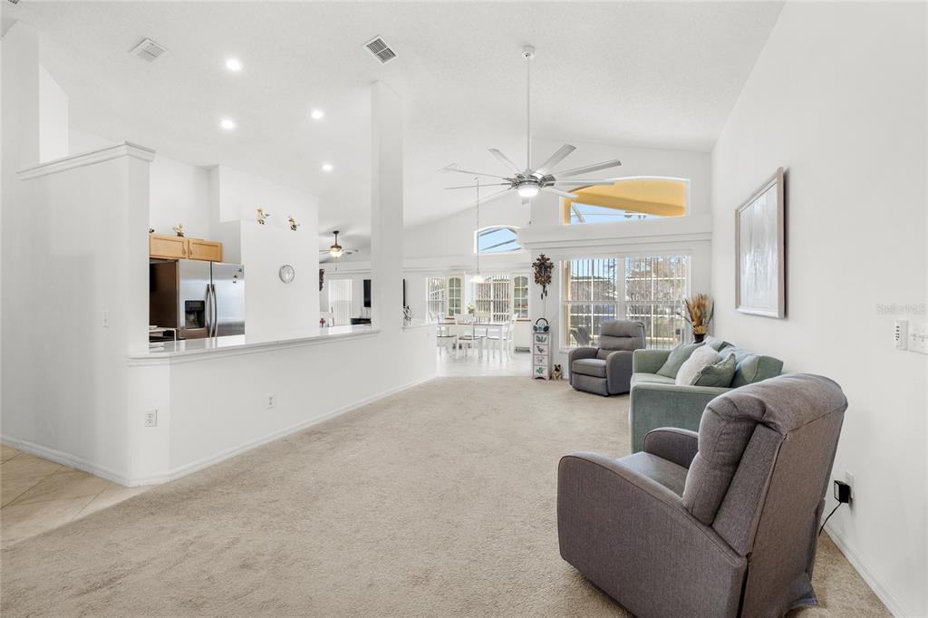 A spacious living room with beige carpeting, white walls, and a large ceiling fan — 235 BALLYSHANNON DRIVE, DAVENPORT, FL