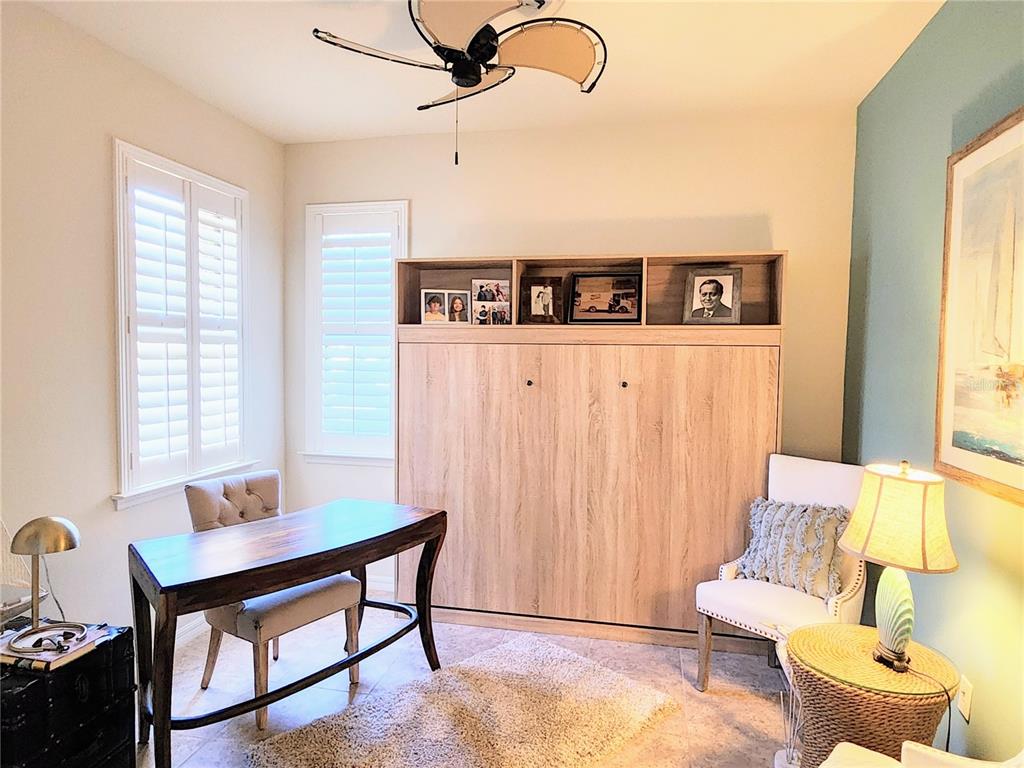 A home office featuring a light wood Murphy bed, a desk, and a sitting area — 13892 ALAFAYA STREET, VENICE, FL