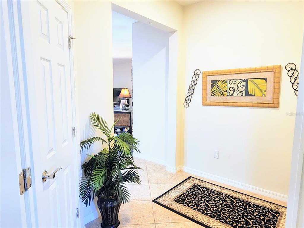 A tiled entryway features a potted plant, a decorative rug, and wall art — 13892 ALAFAYA STREET, VENICE, FL