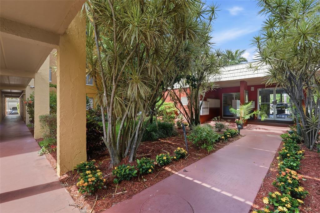 A paved walkway leads to the entrance of a building surrounded by trees and landscaping — 2366 E MALL DRIVE UNIT 403, FORT MYERS, FL
