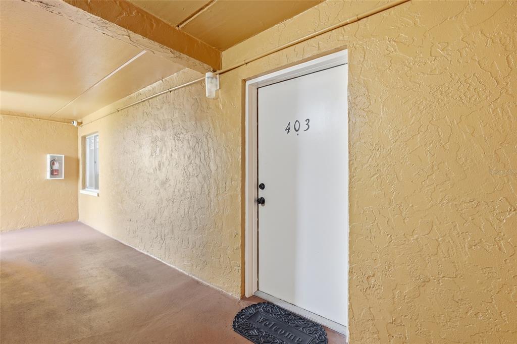 A white apartment door numbered 403 is set in a textured yellow exterior wall — 2366 E MALL DRIVE UNIT 403, FORT MYERS, FL