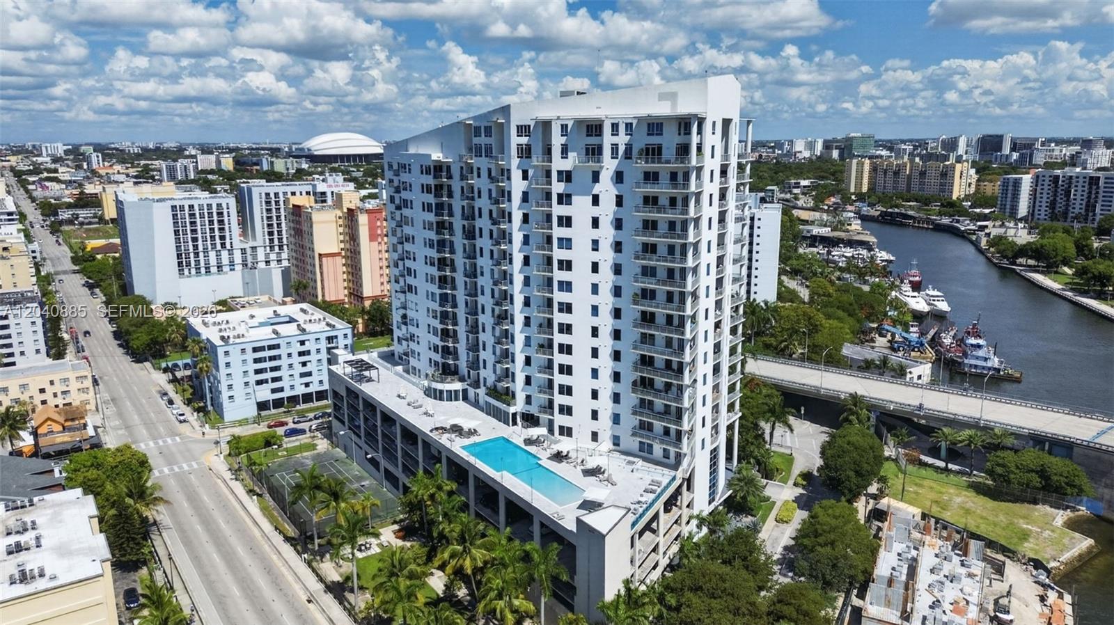 An aerial view shows a tall white apartment building with a rooftop pool and deck — 10 SW South River Dr # 1005, Miami FL 33130, MIAMI, FL