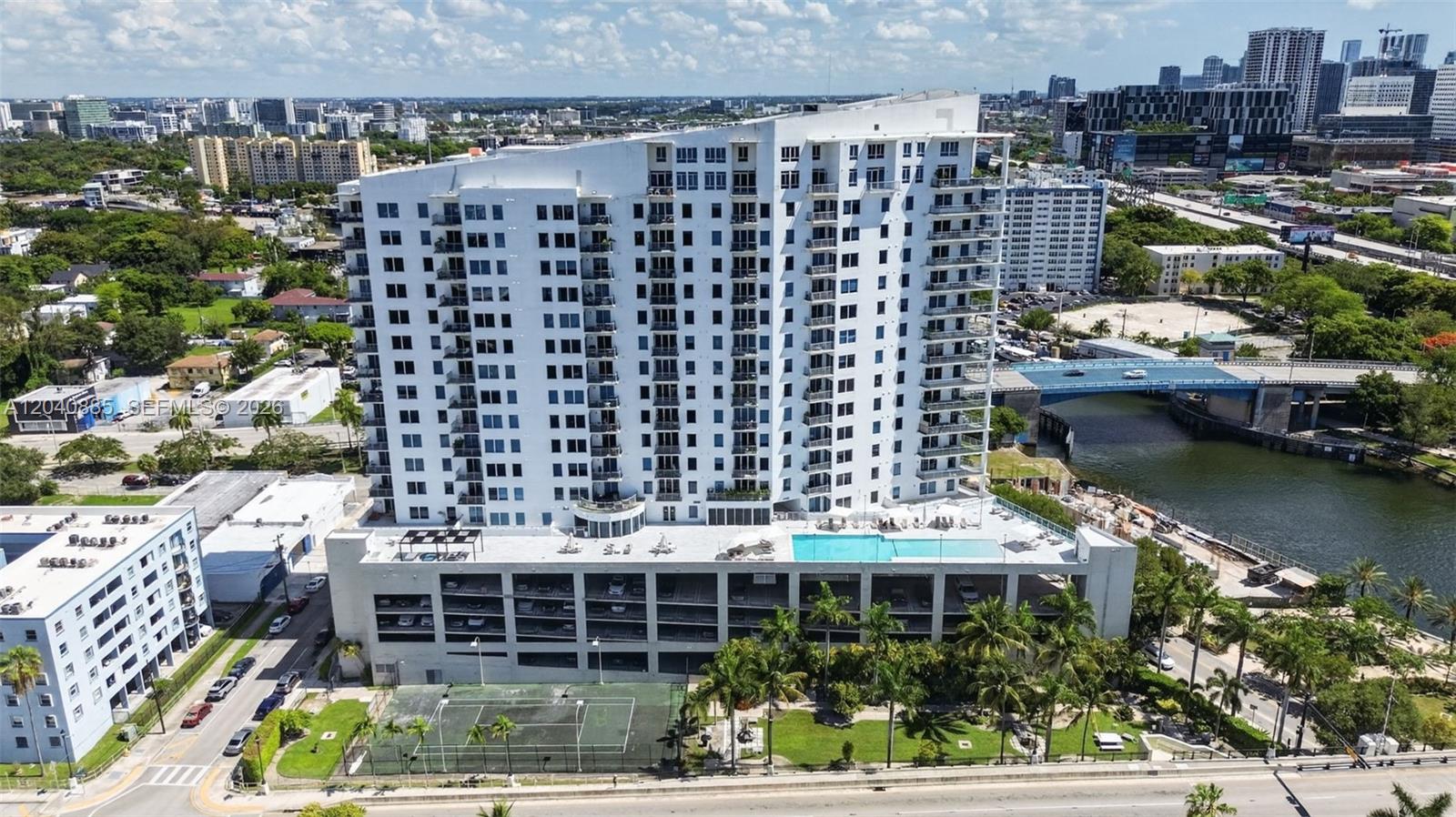 An aerial view shows a tall residential building with a pool deck and tennis court — 10 SW South River Dr # 1005, Miami FL 33130, MIAMI, FL