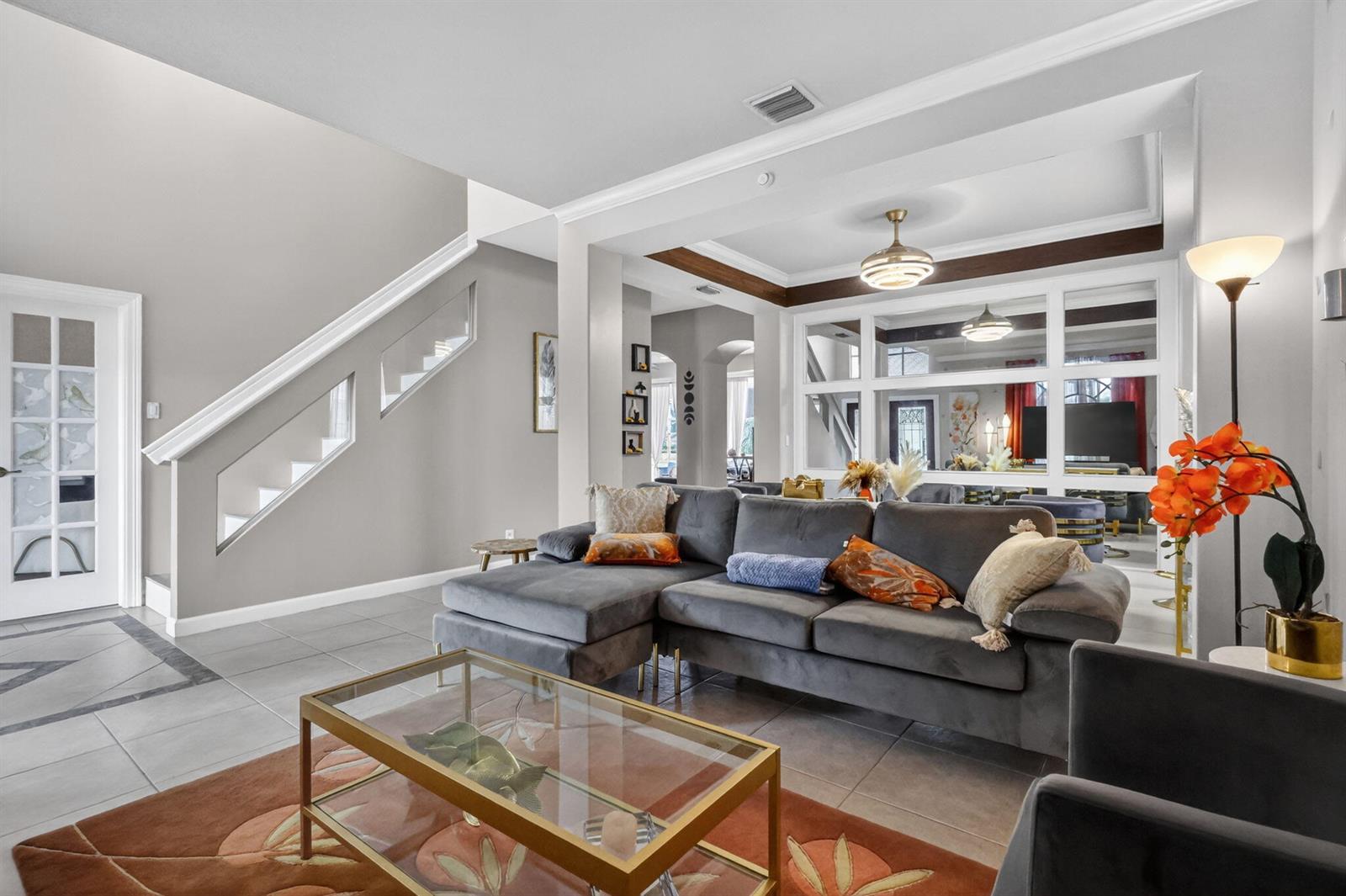 A living room with a grey sectional sofa, glass coffee table, and a staircase — 3620 Hamilton Key, West Palm Beach FL 33411, WEST PALM BEACH, FL