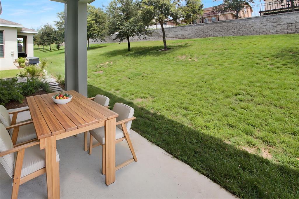A wooden patio table and chairs sit on a concrete porch overlooking a grassy yard — 987 WAX MYRTLE AVENUE, MINNEOLA, FL