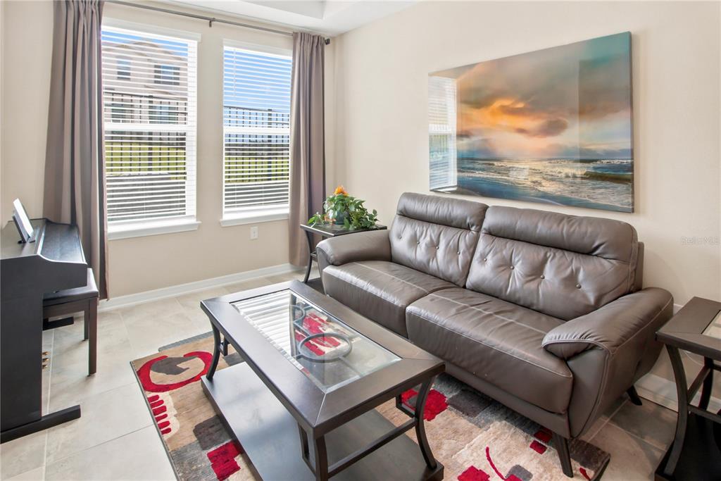 A living room features a brown leather sofa, a glass-top coffee table, and a piano — 987 WAX MYRTLE AVENUE, MINNEOLA, FL