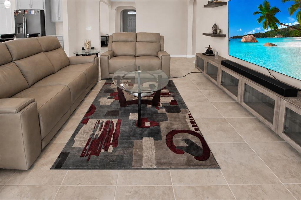 A living room features a beige sofa, a loveseat, a glass coffee table, and a television — 987 WAX MYRTLE AVENUE, MINNEOLA, FL