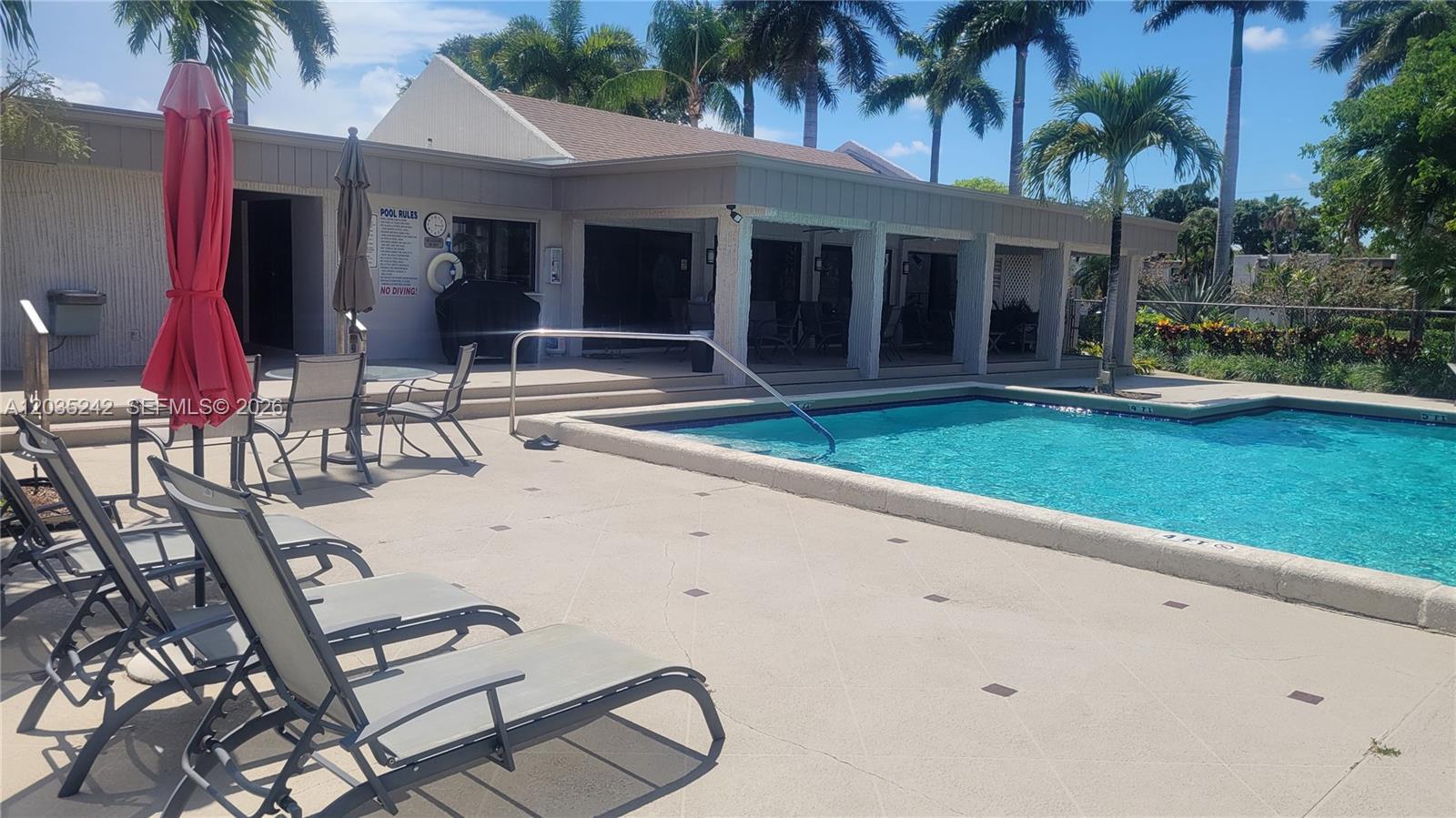 A swimming pool with lounge chairs and a covered patio area under a blue sky — 6666 Spring Bottom Way # 179, Boca Raton FL 33433, BOCA RATON, FL