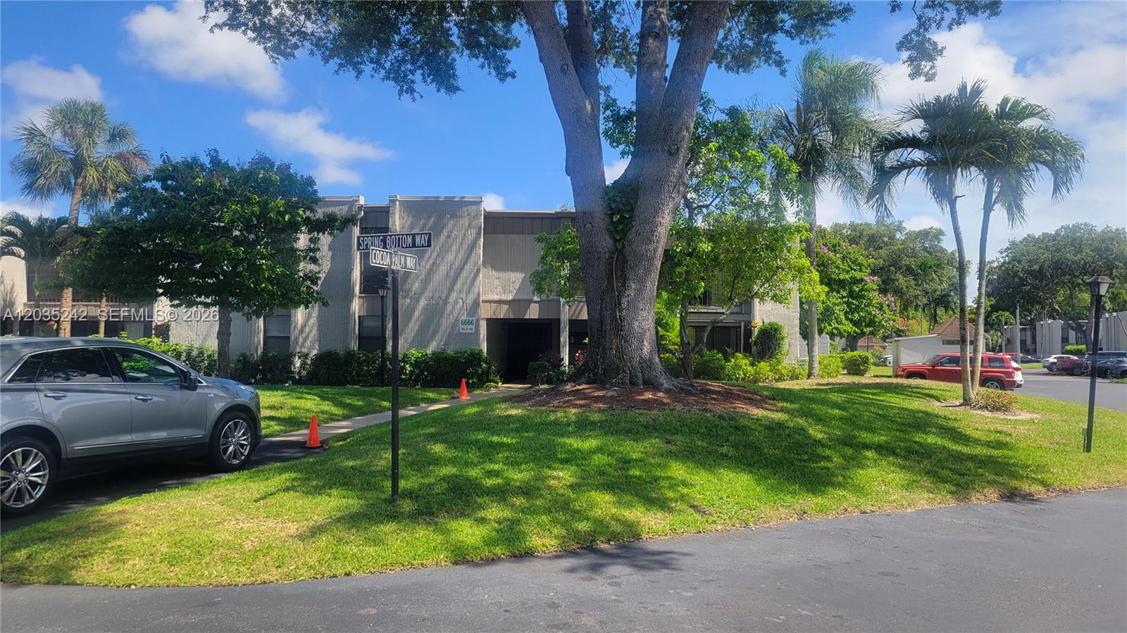 A two-story apartment building stands behind a large tree, a street sign, and a car — 6666 Spring Bottom Way # 179, Boca Raton FL 33433, BOCA RATON, FL