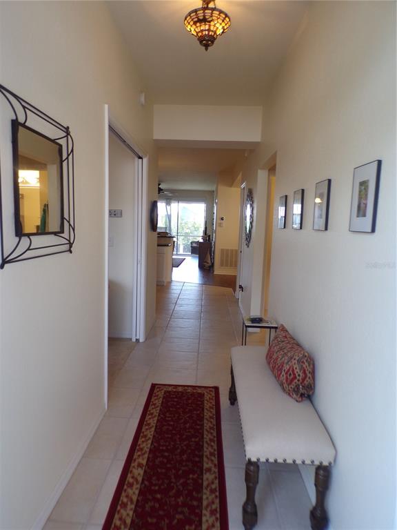 A hallway features a tiled floor, a runner rug, a bench, and wall-mounted artwork — 2002 BAL HARBOR BOULEVARD UNIT 2312, PUNTA GORDA, FL