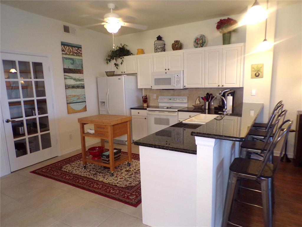 A kitchen features white cabinets, dark granite countertops, a wooden island, and a breakfast bar — 2002 BAL HARBOR BOULEVARD UNIT 2312, PUNTA GORDA, FL