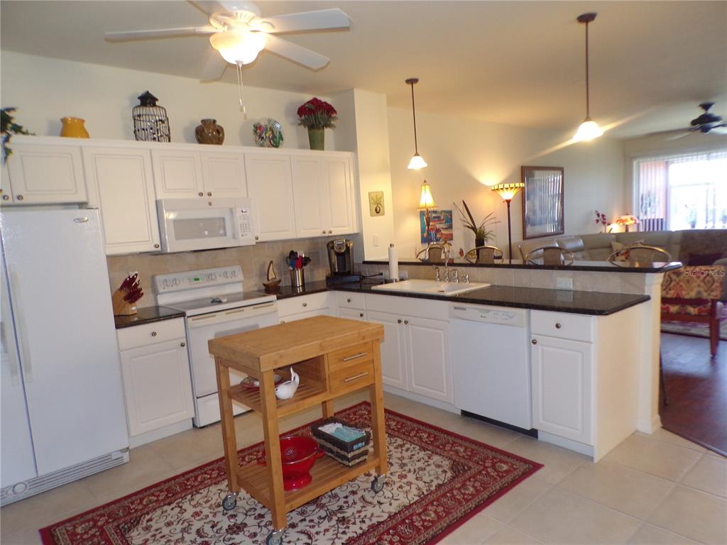 A kitchen with white cabinets, dark countertops, a rolling wooden island, and a red rug — 2002 BAL HARBOR BOULEVARD UNIT 2312, PUNTA GORDA, FL