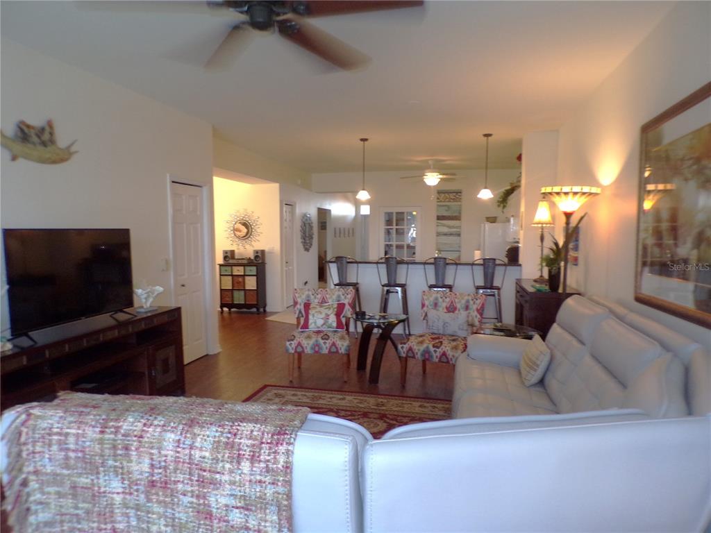 A living room with a white sofa, patterned chairs, and a kitchen breakfast bar — 2002 BAL HARBOR BOULEVARD UNIT 2312, PUNTA GORDA, FL